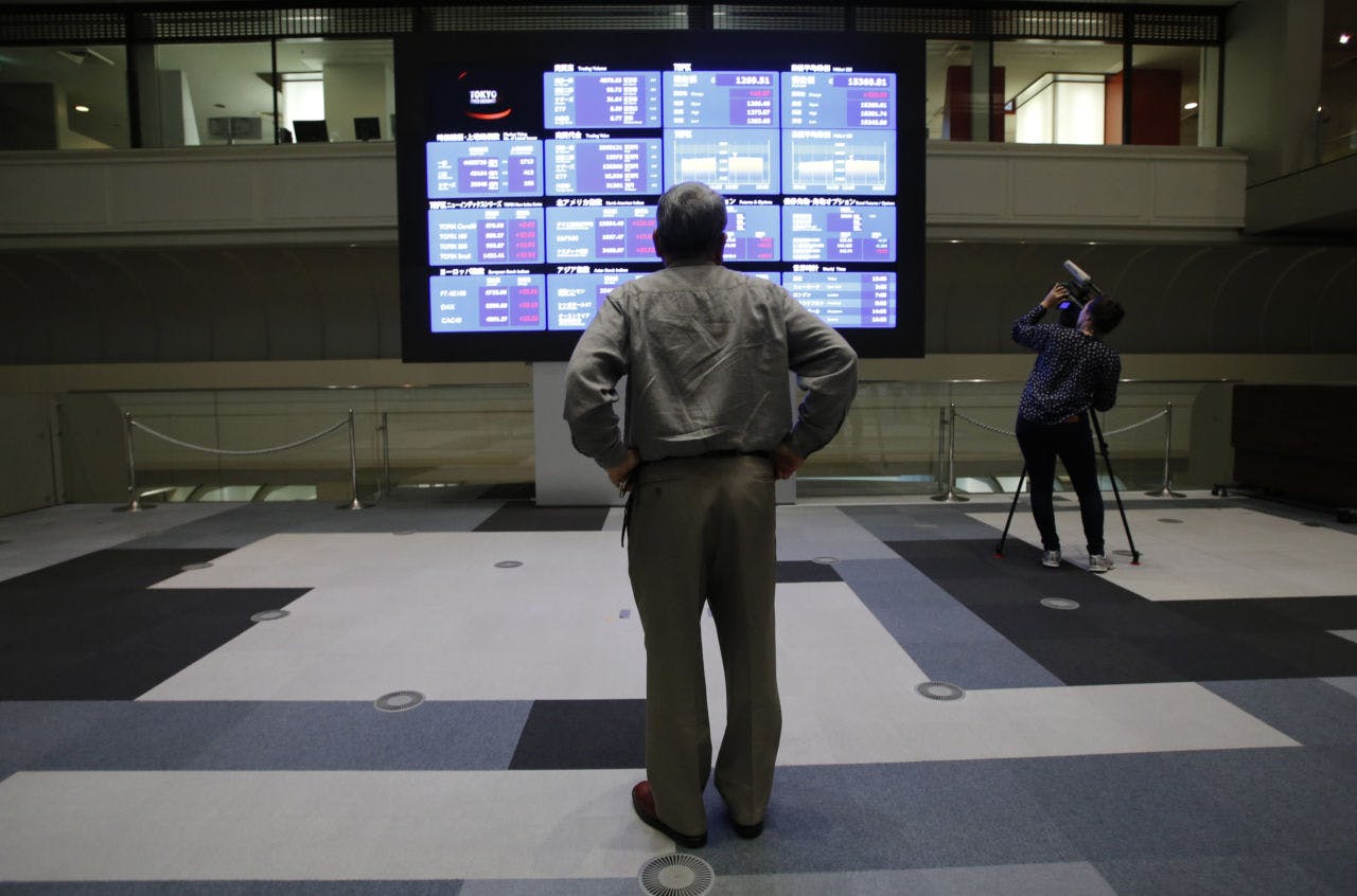 東京証券取引所で株価ボードを見る人