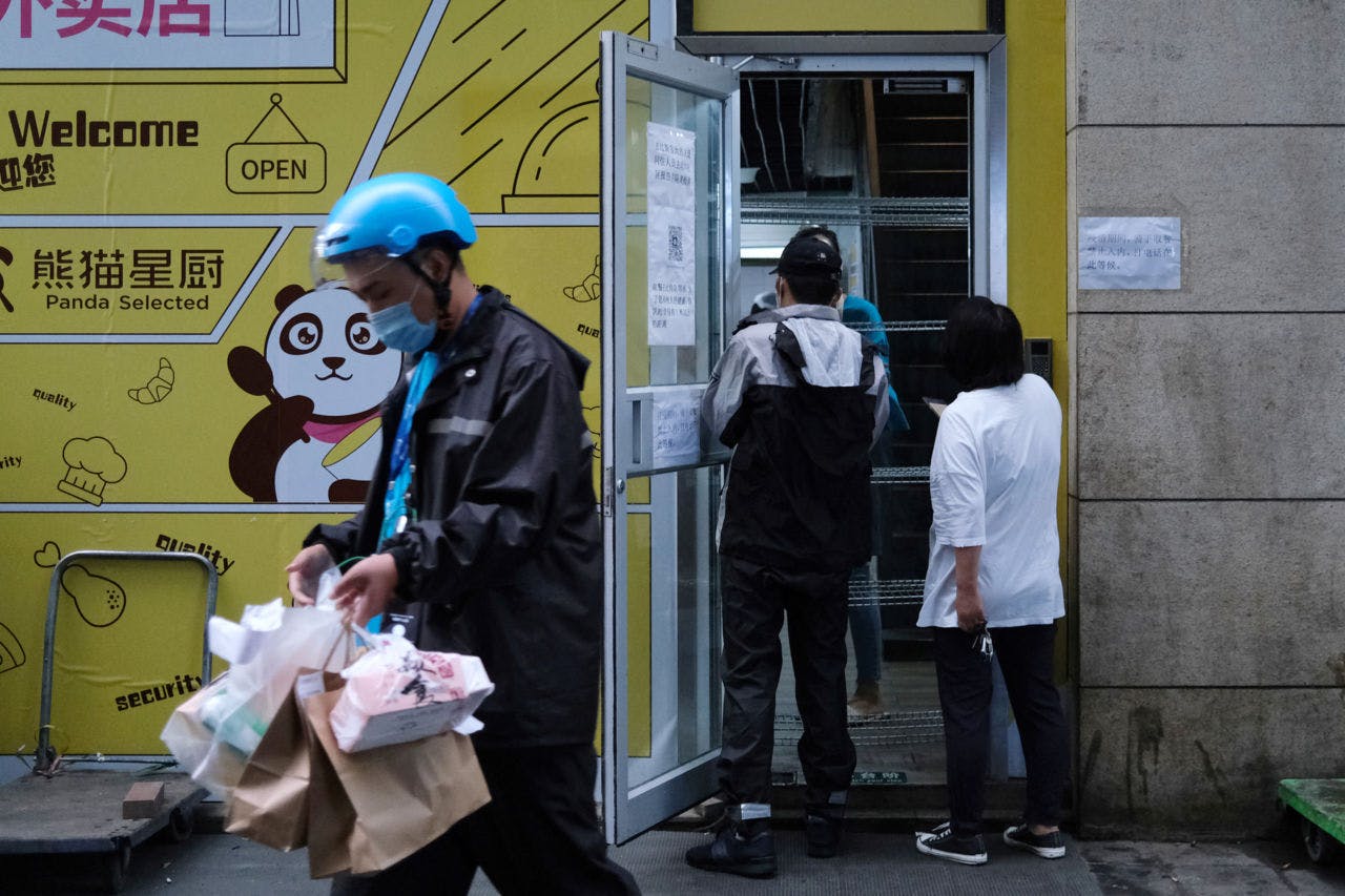 北京の飲食店から配達用の注文品をピックアップするデリバリーの男性