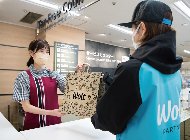 お店のスタッフから商品を受け取るウォルトの配達員