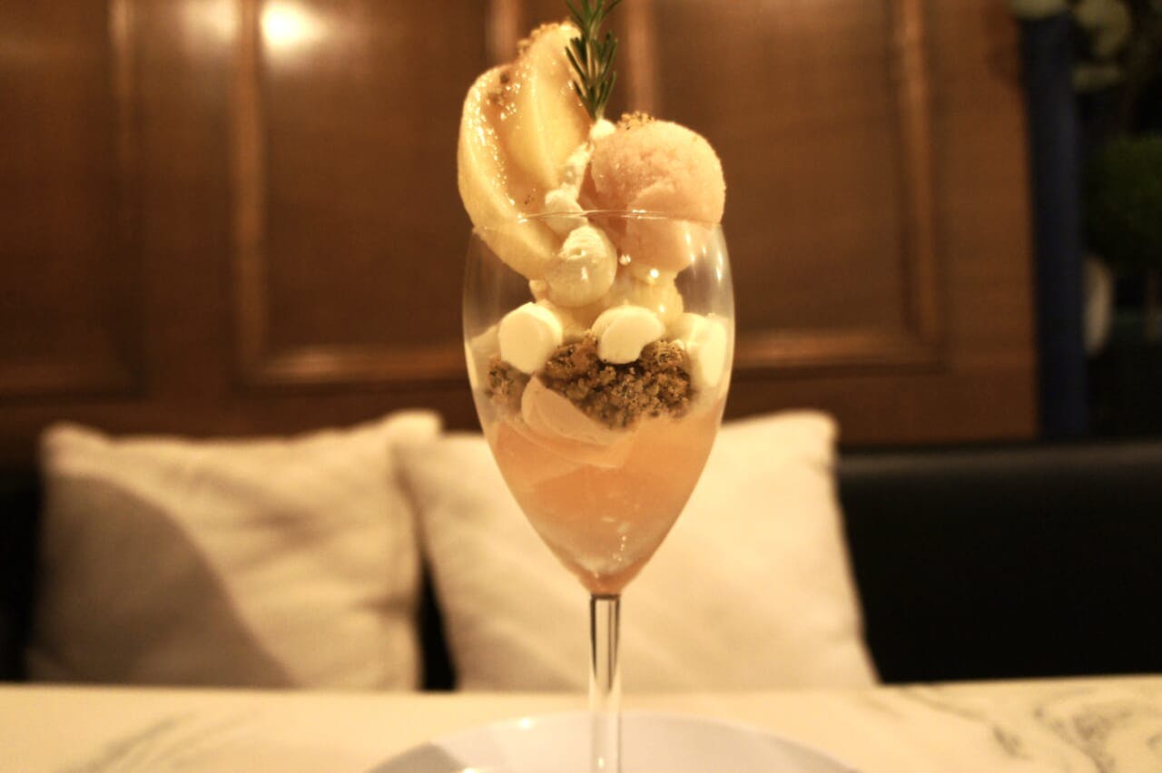神戸・元町の人気カフェ「Hachi Cafe」の「桃とアールグレイのパフェ」。桃のジュレや塩を効かせたローズマリーのクランブル、アールグレイのソルベ、フレッシュの桃などを組み合わせる