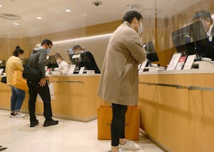 松屋銀座の免税カウンターで手続きを取る訪日外国人旅行客ら