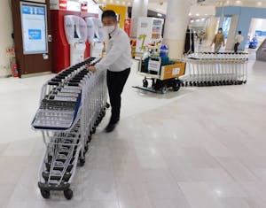 ショッピングカート運搬支援ロボットの実演を行うメーカーの従業員