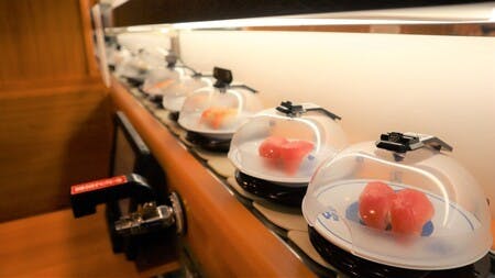 くら寿司で導入された回転レーンの寿司皿を覆う「抗菌寿司カバー」の不審な動きを検知するAIカメラ