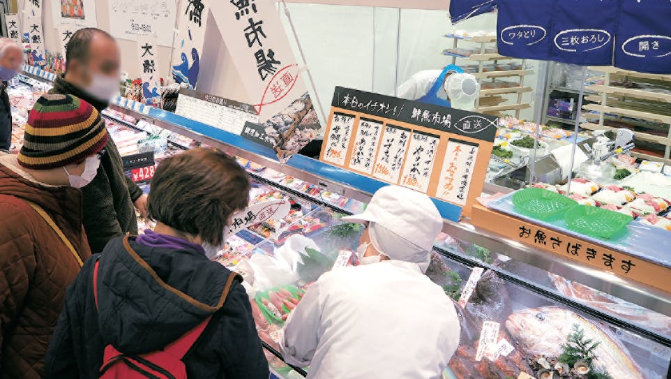 鮮魚売場にて客とコミュニケーションをとる店員