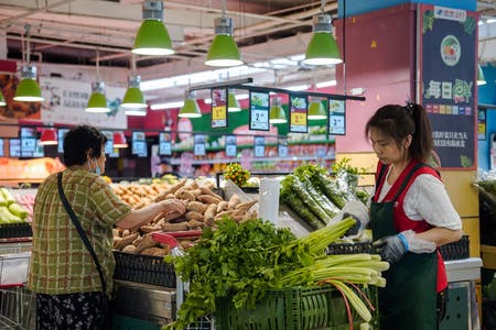 中国北京のスーパーの野菜売り場で買い物する人たち