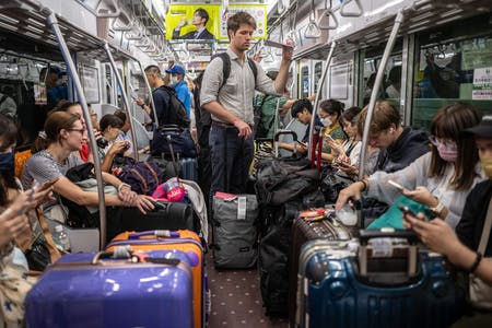 成田空港から東京へと鉄道で向かう旅行者ら