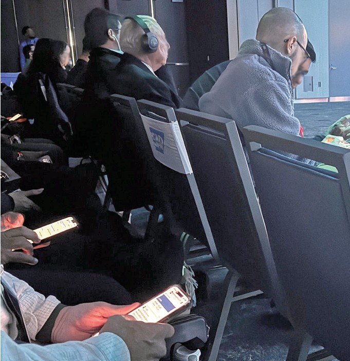 NRFのセッション会場で見られるスマホのAI翻訳を眺める参加者