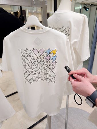 目が見えなくても触って形が分かるほか、紫外線を当てると色が変わる仕掛けもある凹凸加工のロゴが付いたＴシャツ