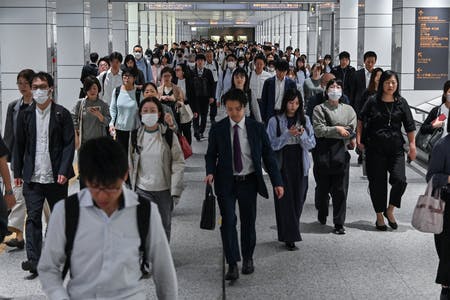 東京の新宿駅近くを歩く通勤客ら